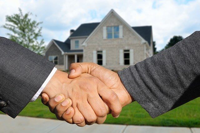 Zwei Menschen schütteln die Hände über ein Immobiliengeschäft