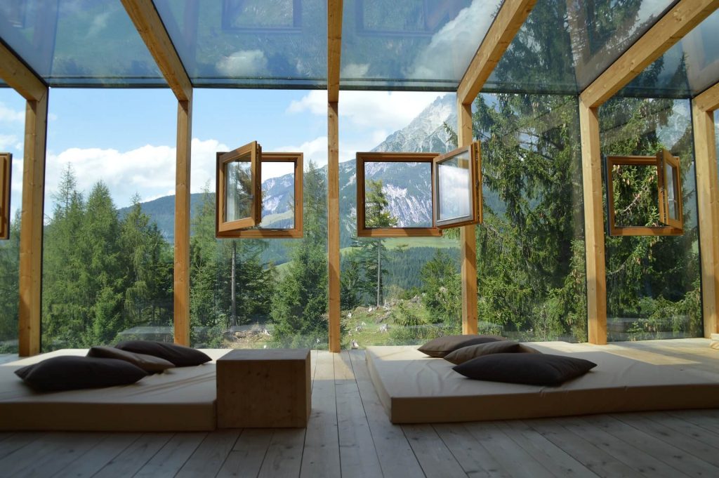 Das Bild eines Hausfensters, das eine malerische grüne Landschaft einrahmt, lädt die Schönheit der Natur ins Innere ein und bietet einen ruhigen Blick auf die üppige Umgebung.