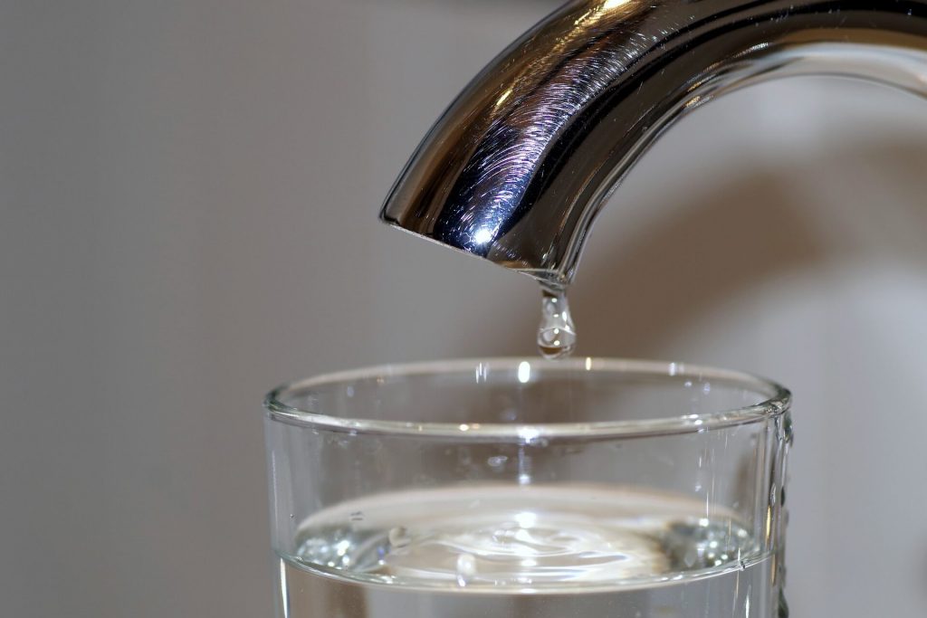 Ein Bild, das einen Wasserhahn zeigt, der in ein Glas tropft, stellt das Konzept der Wassereinsparung, der Beständigkeit oder der erfrischenden Natur von sauberem Trinkwasser dar.